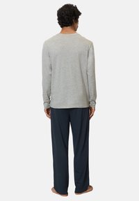 Chemise grise à manches longues avec un col rond associée à un pantalon bleu marine ample, doté d'un tissu lisse et d'une coupe décontractée.