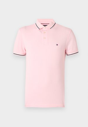 Różowa koszulka polo wykonana z miękkiej bawełny z klasycznym kołnierzykiem. Posiada trzy złote guziki oraz granatowo-białe paski na rękawach.