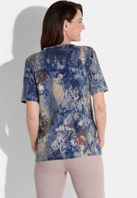 Korte mouwen shirt met een blauw en beige bloem- en slanghuidpatroon, met een relaxte pasvorm en een ronde hals.