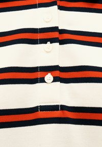 White, navy, and red horizontal striped fabric with three white buttons sewn in a vertical line on a knit garment.