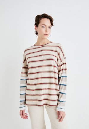 Beige színű, hosszú ujjú csíkos felső, vízszintes piros, barna és kék csíkokkal, kontrasztos kék és barna ujjrészletekkel, puha tapintású anyagból.