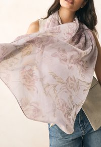 Lengvas, permatomas rausvas šalikas su gėlių raštais kremine ir subtilia auksine spalvomis, laisvai uždėtas ant pečių, lygios tekstūros.