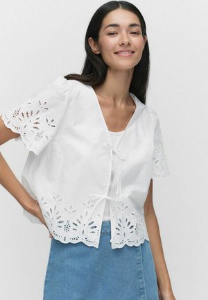 White cropped blouse with lace trim, short puff sleeves, and a bow tie closure. Made of lightweight fabric with floral embroidery accents.