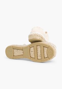 Espadrilla beige con toma in tessuto testurizzato e rifinitura in juta intrecciata. La suola in gomma presenta modanature di presa testurizzate. Design piatto e aperto.