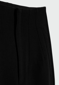 Pantaloni neri su misura con una texture liscia, caratterizzati da una vita strutturata, pieghe e tasche laterali per un design funzionale.