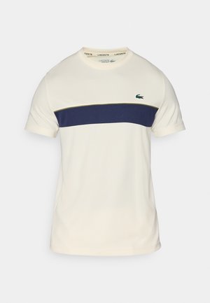 Cream and navy Lacoste t-shirt with a round neckline, short sleeves, and a horizontal color block. Features a green crocodile logo.