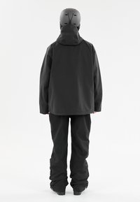 Svart vattentät snöbräda jacka med huva och matchande byxor. Slät textur, avslappnad passform och förstärkta sömmar synliga.