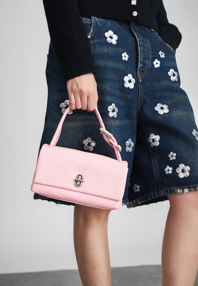 Rozā ādas rokassoma ar taisnstūrveida formu, kurai ir sudraba sprādze un izšūti rokturi, kombinēta ar džinsa šortiem, kas rotāti ar ziedu aplikācijām.