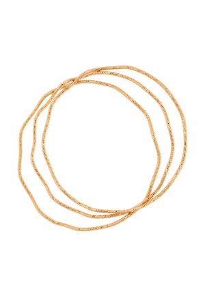 Drie dunne gouden kettingen losjes opgerold tegen een witte achtergrond, waarbij hun fijne, reflecterende textuur wordt benadrukt.