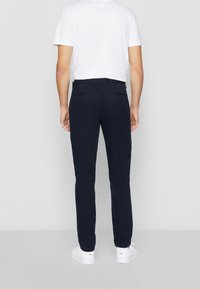 Mörkblå chinos med smal passform, tillverkade av bomullsblend. Funktionen inkluderar två bakfickor med knappstängning och midja med bältesslingor.