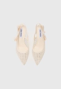 Cream-colored high-heeled slingback shoes with pointed toes, embellished with silver studs, and featuring a decorative bow on each side.