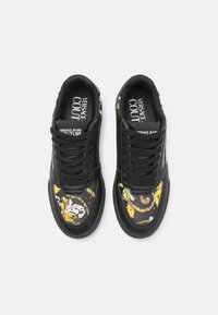 Zwarte sneakers met een patroonontwerp en gele en witte accenten. Gladde leren stof, traditionele vetersluiting en logo-details.