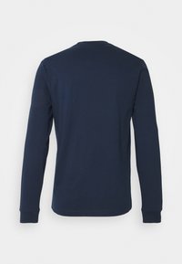 T-shirt à manches longues bleu marine en coton. Présente un col rond et des manches ajustées. Texture lisse sans motifs ni embellissements visibles.