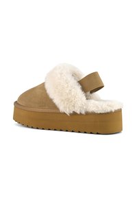Mocassin en suede tan avec une doublure en fausse fourrure crémeuse et une bande, doté d'une épaisse semelle en caoutchouc texturé.
