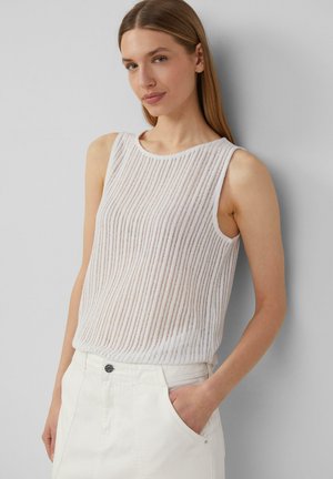 Haut sans manches blanc à texture côtelée, col rond et coupe ample. Associé à un short en denim blanc taille haute.