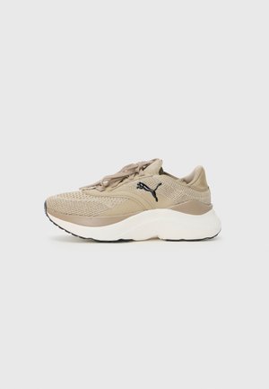 Beige Sneaker mit einem strukturierten Strick-Obermaterial, gepolsterter Sohle und schwarzem Logo. Verfügt über flache Schnürsenkel und ein rundes Zehendesign.