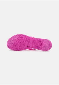 Infradito rosa in gomma con suola testurizzata, caratterizzata da piccole impugnature circolari e branding. Il design è semplice e con punta aperta.