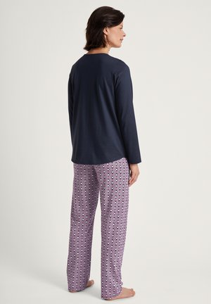 Haut à manches longues bleu marine avec un col rond associé à un pantalon violet clair à motifs géométriques, en tissu doux.