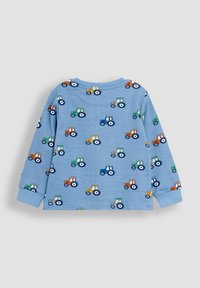 Blauwe shirt met lange mouwen, versierd met een herhaald patroon van gekleurde tractors. Het materiaal lijkt zacht en textuur te hebben, met geribde manchetten.