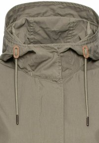 Leichte olivgrüne Jacke mit hohem Kragen, verstellbaren Kordeln und kontrastierenden Nähten. Sie zeichnet sich durch eine glatte Textur und ein minimalistisches Design aus.