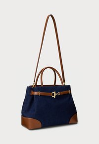 Granatowa torebka materiałowa z brązowymi skórzanymi akcentami, podwójnymi uchwytami, regulowanym paskiem na ramię i złotymi detalami.