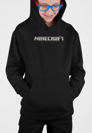 Felpa nera con cappuccio e tasca frontale, caratterizzata dalla scritta "MINECRAFT" in un grande font grigio a blocchi sul petto. Tessuto morbido in flanella.