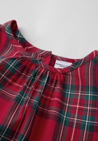 Rode geruite jurk met een geplooide halslijn, voorzien van groene en witte accenten op een zachte stof, die een klassieke tartanprint tentoonstelt.