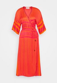 Röd och orange mönstrad omslagsklänning med korta ärmar, knytning i midjan och en flödande siluett. Slät tygtextur och anmärkningsvärda geometriska mönster.