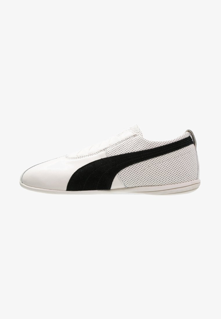 Baskets en cuir blanc avec une bande en suède noir, talon blanc perforé et semelle blanche plate, vues de profil.