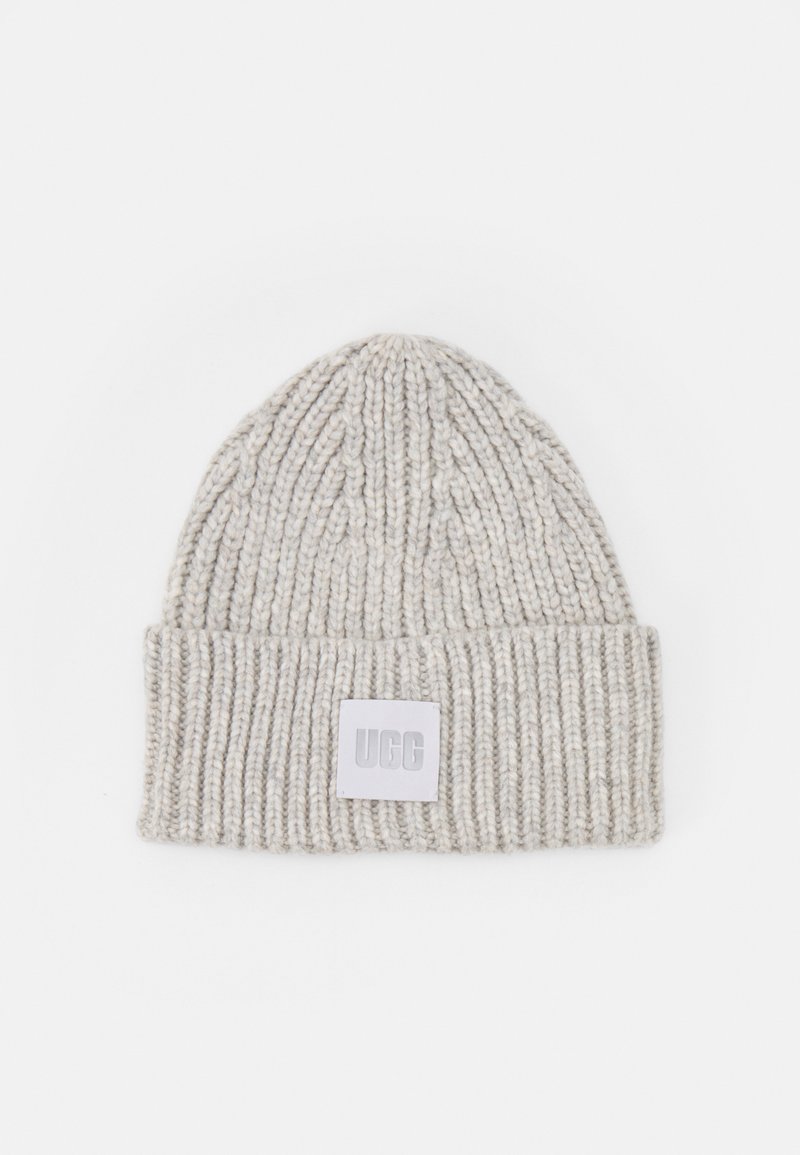 Lys grå strikket lue med ribbet tekstur og brettkant. Har et firkantet UGG-logo-patch foran.