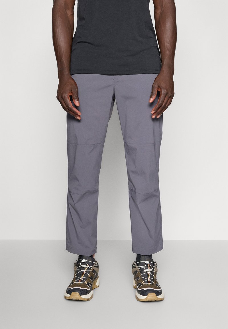 Gray, lightweight, stretch fabric pants with a smooth texture and side seams. Paired with black and tan athletic shoes featuring laces.