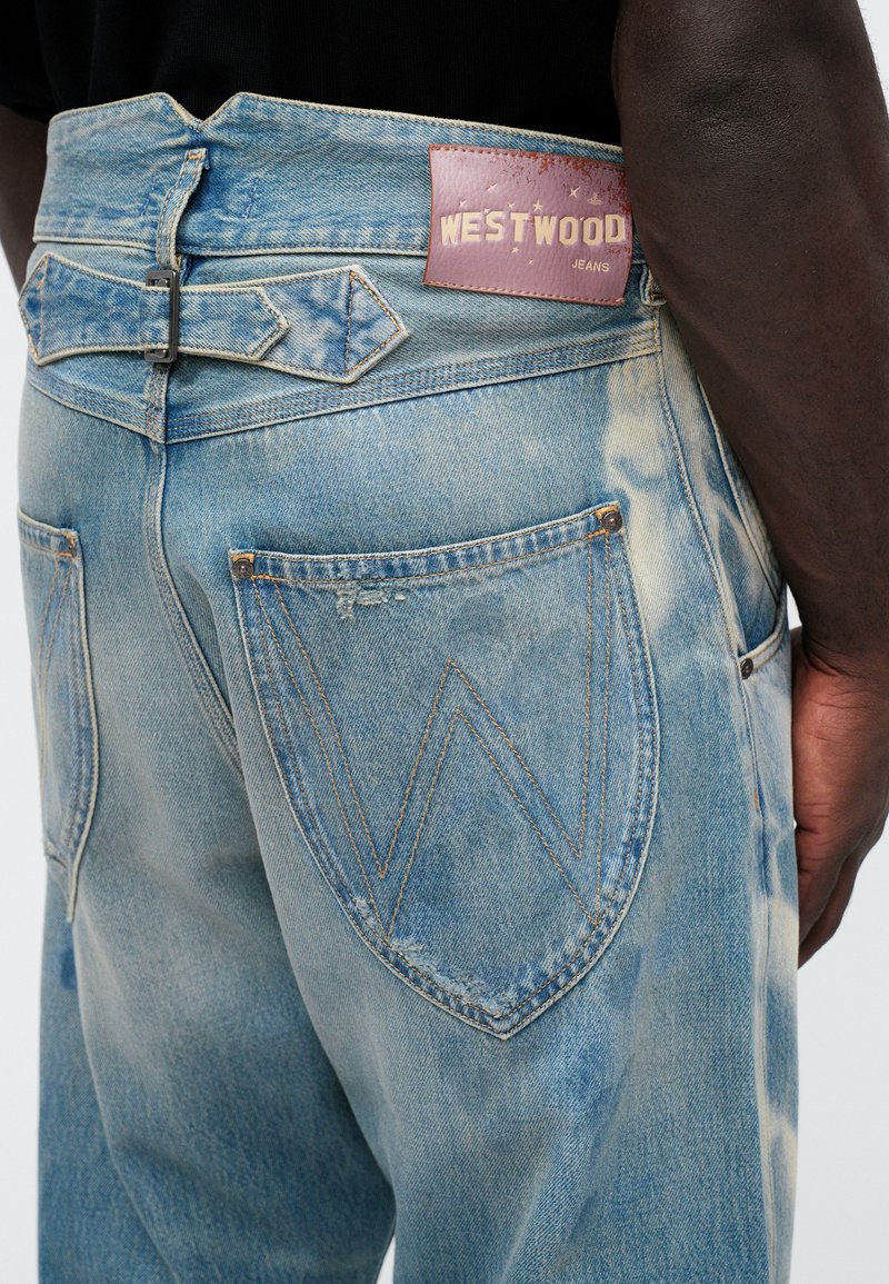 Ljusblå denimjeans med en läderlapp märkt "WESTWOOD", en unik bakfickdesign och slitna detaljer.