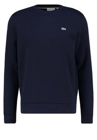 Sweatshirt bleu marine en coton doux, avec un col rond, des manches longues, des poignets côtelés et un petit logo de crocodile vert sur la poitrine.