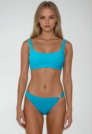 Set di bikini azzurro chiaro composto da un top con scollatura quadrata e spalline spesse, abbinato a un bottoms a vita bassa, decorato con un accento di conchiglia argentata su un lato.