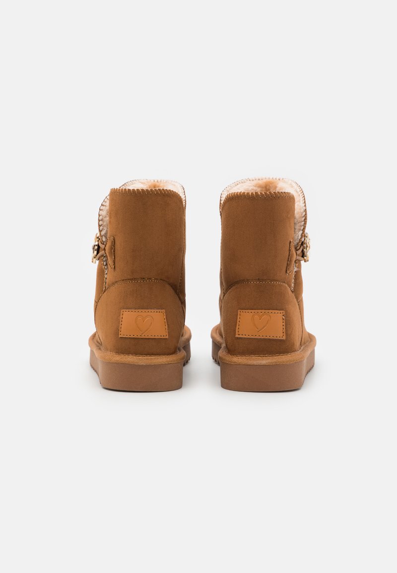 Braune Wildleder-Stiefeletten mit weicher, flauschiger Fütterung, dekorativem Reißverschluss an der Seite und strukturierten Gumm soles. Herz-Logo auf der Rückseite.