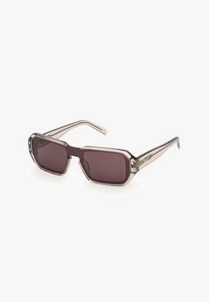 Gafas de sol rectangulares con montura gris traslúcida y lentes oscuras, con tachuelas metálicas decorativas cerca de las bisagras.
