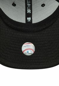 Intérieur d'une casquette de baseball noire montrant l'étiquette de taille "39THIRTY" et un autocollant d'authenticité officiel de la Major League Baseball.