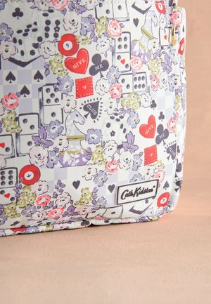 Egy textiltáska részlete, amely virágos, kártyajelképes, kockás, sakkfigurás és billiárdgolyós mintázattal rendelkezik, rajta a "Cath Kidston" márkajelzéssel.