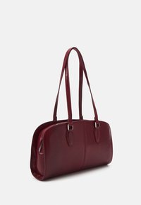 Sac à main en cuir bordeaux avec deux longues poignées, forme rectangulaire, texture lisse et accents de quincaillerie argentée. Fermeture zippée sur un côté.