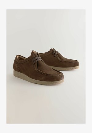 Braune Wildlederschuhe mit runder Spitze, Schnürdesign und strukturiertem Gummisohle. Merkmale sind eine Nahtverzierung entlang des Schaftes.