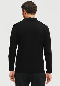 Czarna, długosleeve polówka sweter z kołnierzykiem, gładka faktura i luźny krój, pokazana z tyłu. Charakteryzuje się minimalistycznym wyglądem.