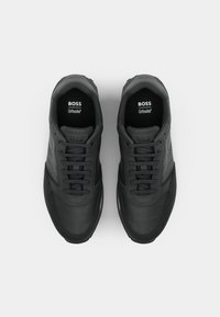 Czarne sportowe sneakersy z górą wykonaną z gładkiej skóry i tkaniny, wyposażone w siateczkowy język, okrągłe sznurowadła oraz branding Ortholite na wkładce.