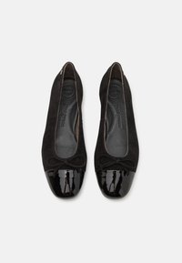 Schwarze Wildleder-Ballerinas mit einer glänzenden schwarzen Lackeinfassung, versehen mit einem kleinen Schleifchen vorne und einer weichen Innensohle.