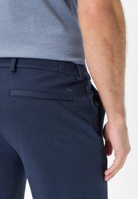 Pantaloni texture blu navy con vestibilità slim, dotati di tasche laterali e una tasca posteriore, realizzati in un tessuto traspirante.