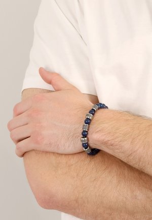 Blaues Perlenarmband mit silberfarbigen Akzenten, das eine Mischung aus glatten und strukturierten Perlen in einem kreisförmigen Design zeigt.