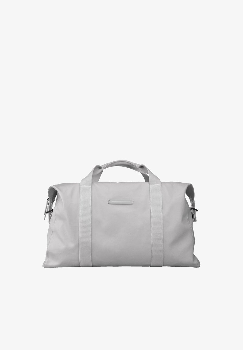 Sac de sport en tissu gris avec des poignées robustes et une bandoulière réglable. Il possède une poche frontale plate et un design lisse et minimaliste.