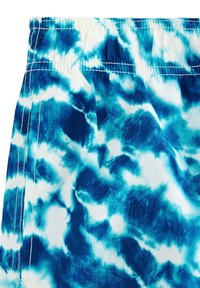 Blå och vita badshorts med ett tie-dye mönster. Har en elastisk midja och ett mjukt, lätt tyg.