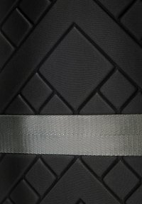 Un matériau noir texturé présente des motifs en losange en relief, complétés par une bande horizontale gris métallique au centre.