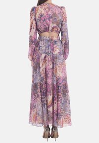 Floral two-piece set featuring long sleeves and a cropped top. The skirt is tiered with a flowing texture in pink, purple, and mauve hues.