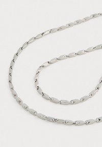 Silver-toned chain necklace with small, elongated diamond-shaped links connected by small circular rings on a light background.